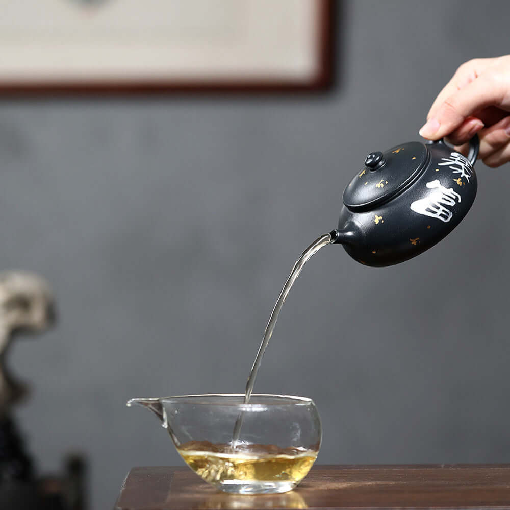 Handmade Yixing purple sand teapot pouring tea into a glass cup, showcasing rich craftsmanship and tea culture.