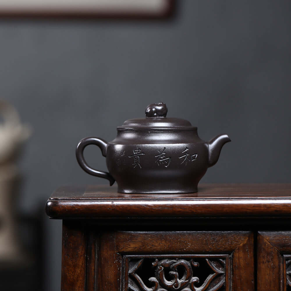 Handmade Yixing purple sand teapot in black clay, showcasing original craftsmanship on a wooden table.
