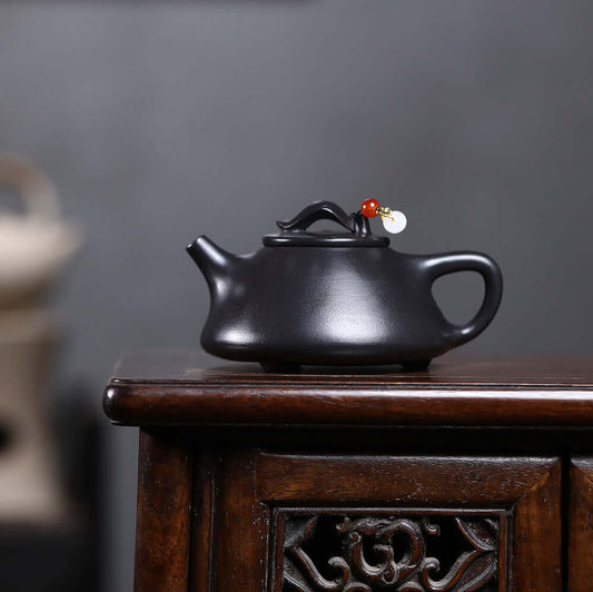 Handmade Yixing purple sand teapot on a wooden table, showcasing its elegant design and craftsmanship.