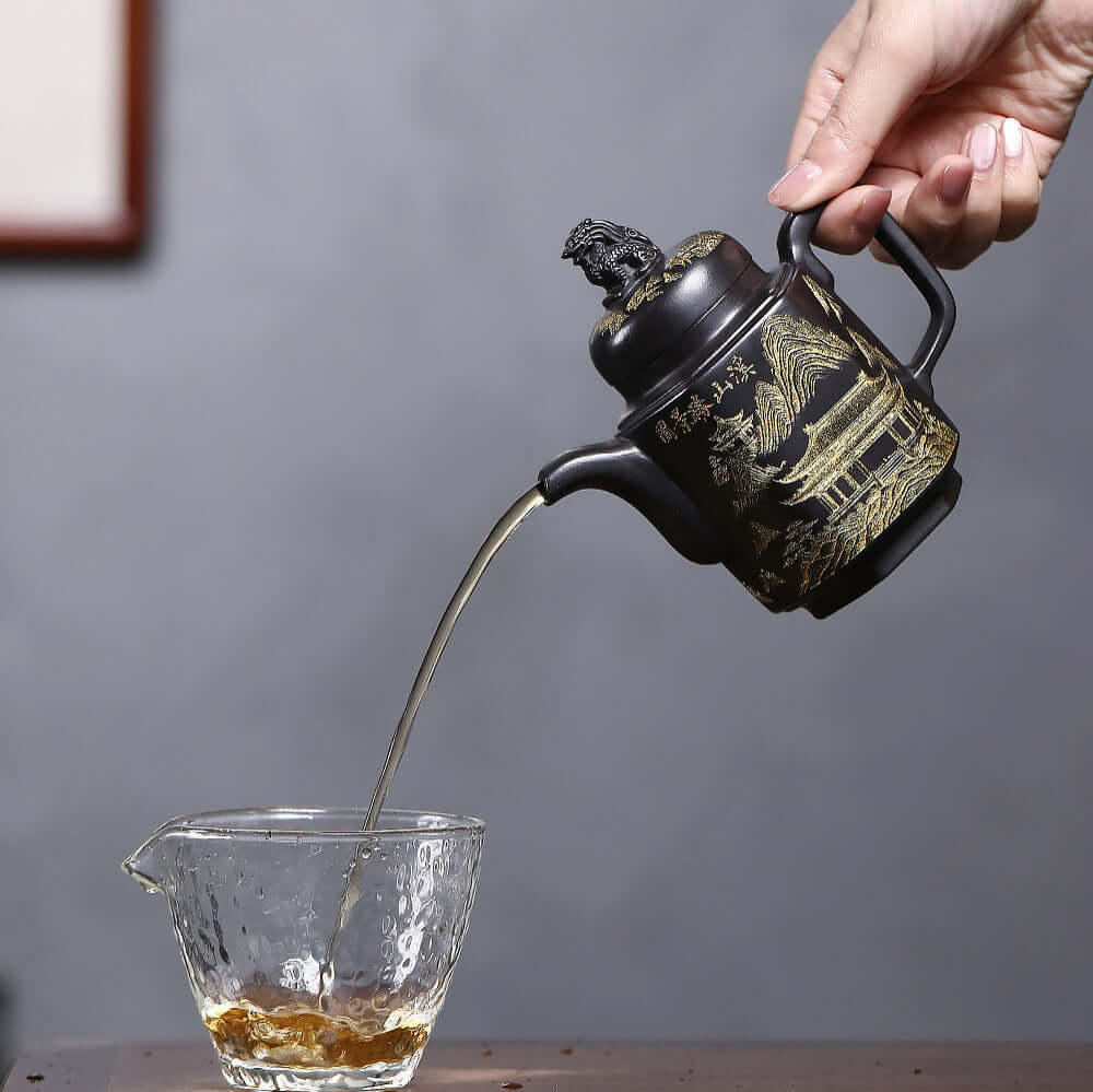 Handmade Yixing purple sand teapot pouring tea into a glass cup, showcasing intricate design and craftsmanship.