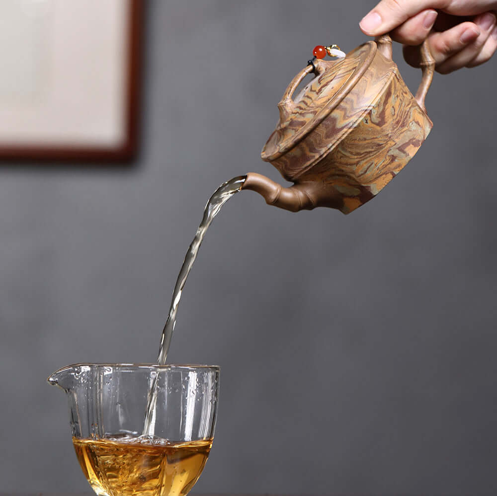 Handmade Yixing purple sand teapot pouring tea into glass, showcasing original craftsmanship and unique twisted mud design.