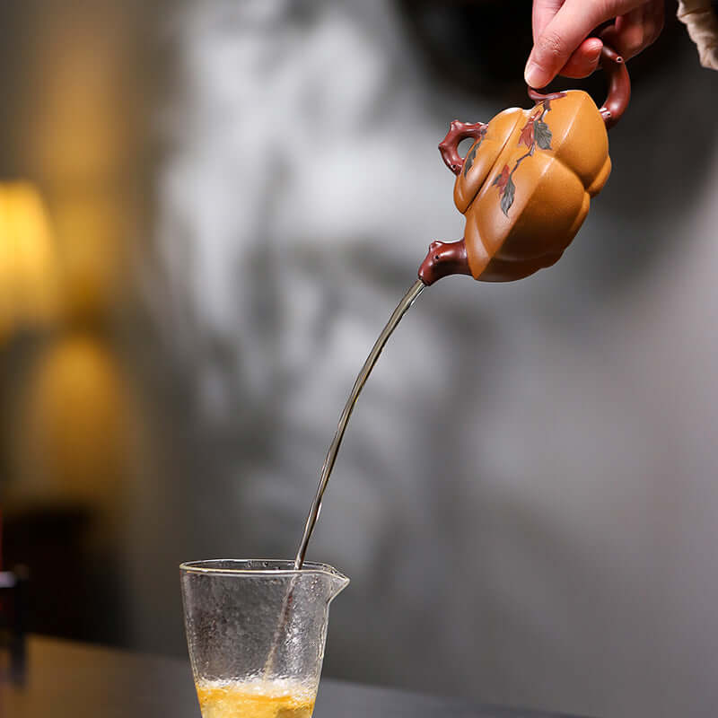 Handmade Yixing purple sand teapot pouring tea into a glass, showcasing elegant design and craftsmanship.