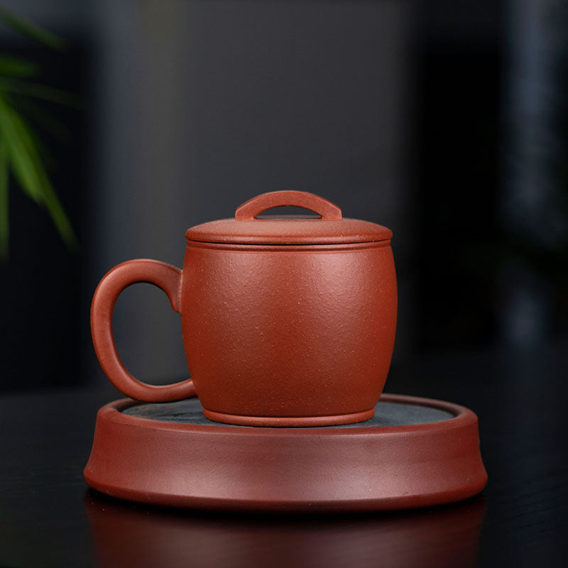 Handmade Yixing purple sand tea cup with lid on a saucer, showcasing authentic craftsmanship.