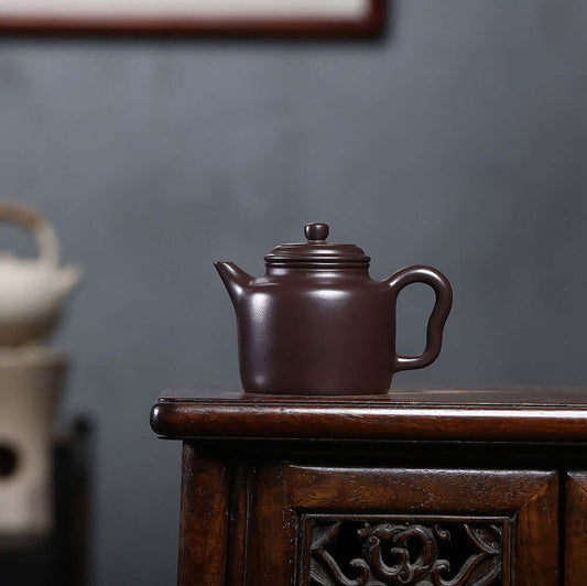 Handmade Yixing purple sand teapot on wooden table, showcasing original craftsmanship and elegant design.