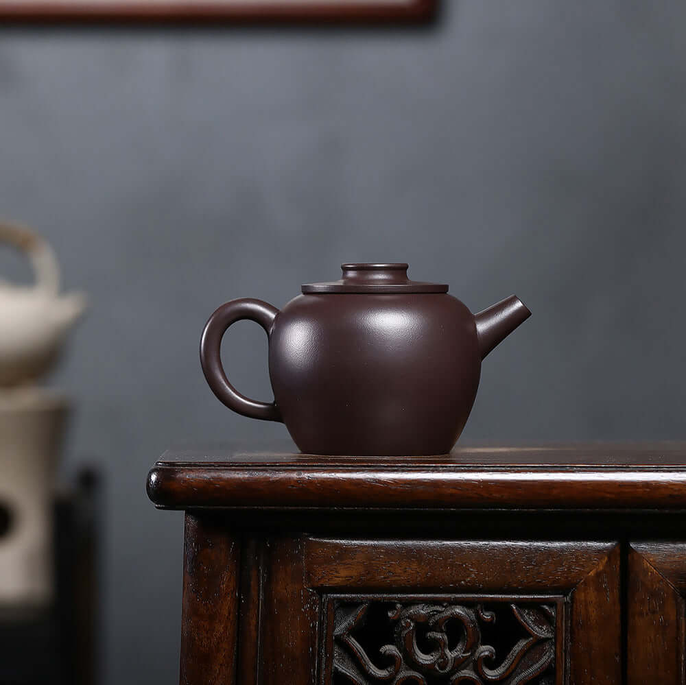 Handmade Yixing purple sand teapot with flat lid on wooden table, showcasing original craftsman design.
