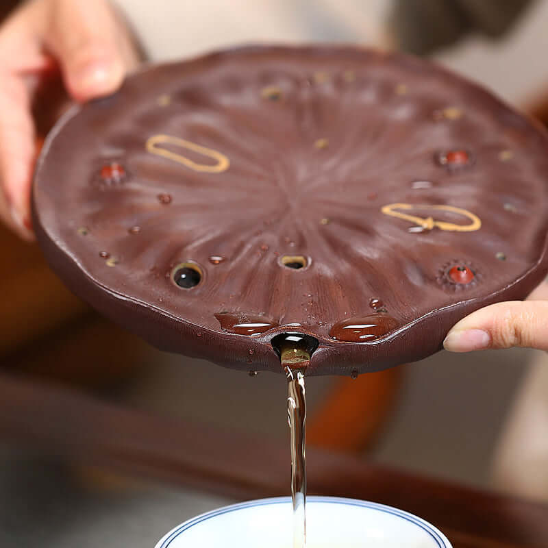Handmade Yixing purple sand lotus pot pad with tea pouring, showcasing craftsmanship and unique design.