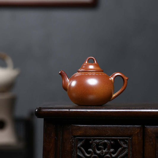 Handmade Yixing purple sand teapot on wooden table, showcasing original craftsmanship and classic design.