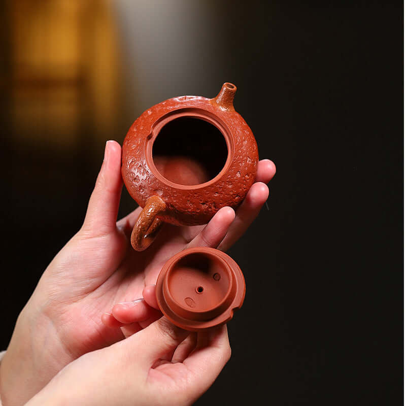 Handmade Yixing purple sand teapot held in hand, showcasing intricate design and removable lid, perfect for kung fu tea.