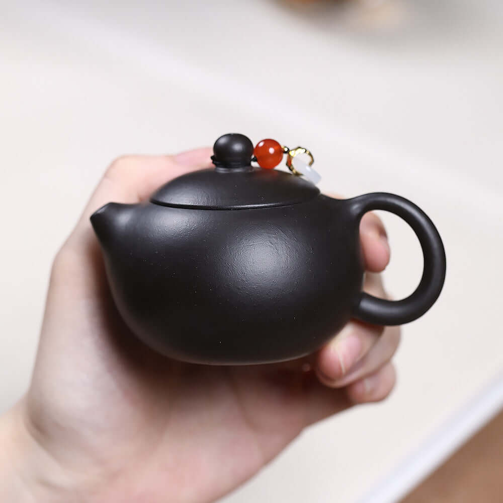 Handmade Yixing purple sand teapot in hand, featuring original design and craftsmanship for Kung Fu tea set.
