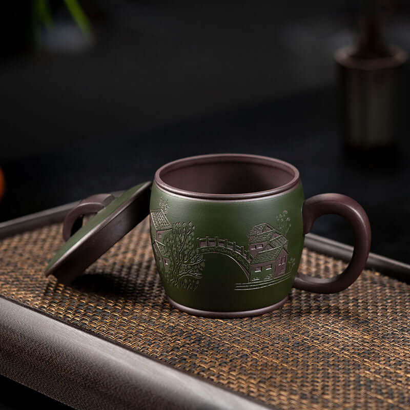 Handmade Yixing purple sand tea cup with green mud, featuring intricate designs, perfect for tea lovers and collectors.