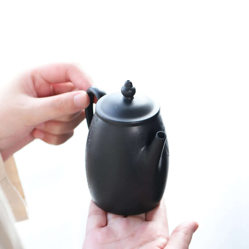 Handmade Yixing purple sand teapot in hand, showcasing elegant design and craftsmanship.