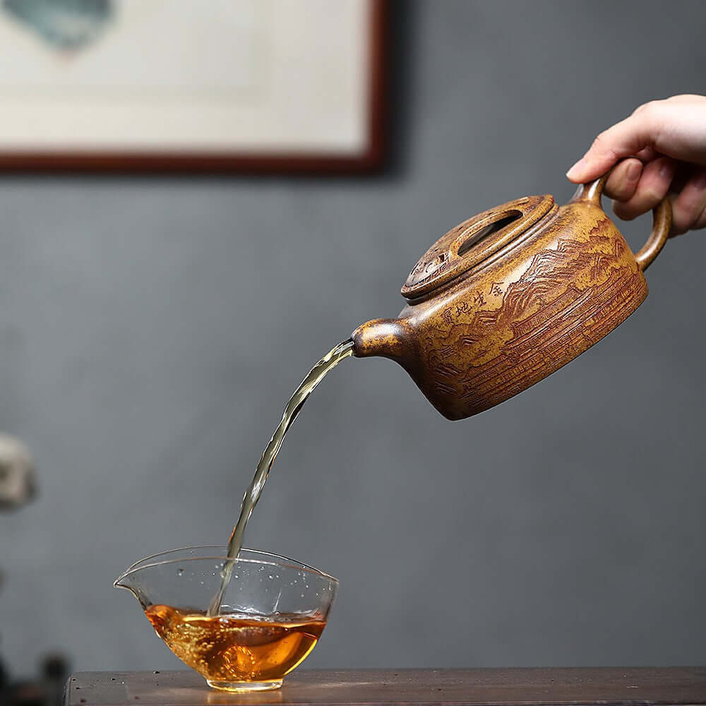 Handmade Yixing purple sand teapot pouring tea into a clear cup, showcasing craftsmanship and traditional design.