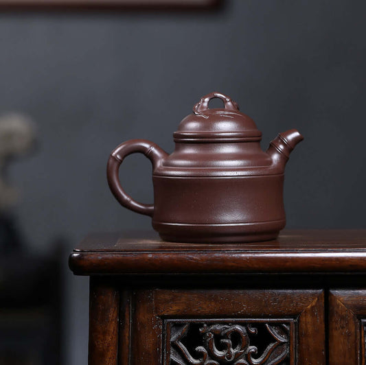 Handmade Yixing purple sand teapot on wooden table, showcasing traditional craftsmanship and unique design.