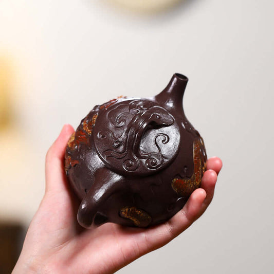 Handmade Yixing purple sand teapot held by a hand, showcasing intricate design and high-quality craftsmanship.
