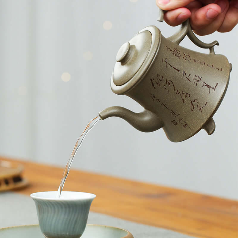 Handmade Yixing purple sand teapot pouring tea into a cup, showcasing its artistic design and craftsmanship.
