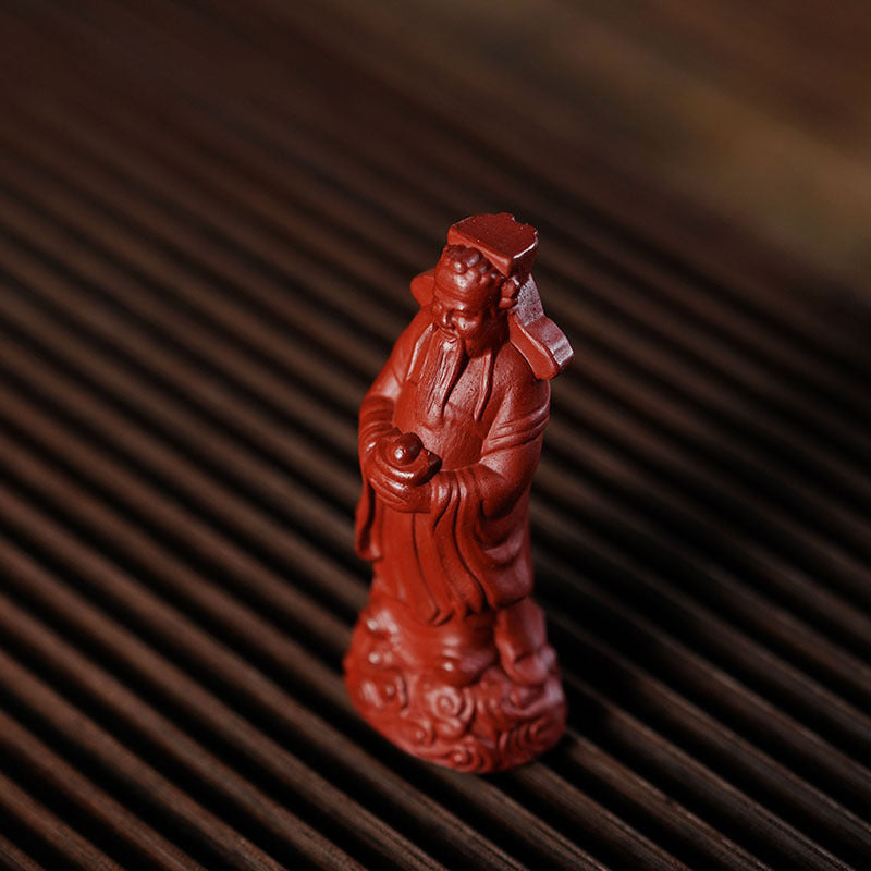 Handmade Yixing purple sand God of Wealth ornament, red robe sculpture for tea set, symbolizing fortune and longevity.