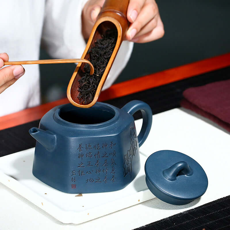 Handmade Yixing purple sand teapot with tea leaves being poured, showcasing unique craftsmanship and design.