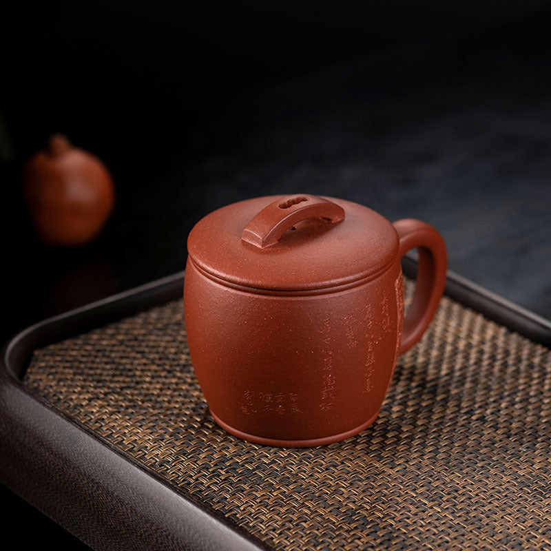Handmade Yixing purple sand cup with lid on a woven tray, showcasing authentic craftsmanship for tea lovers.