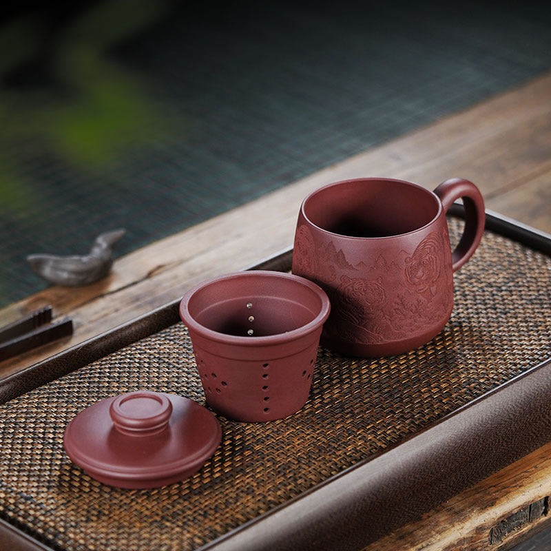 Handmade Yixing purple sand tea set featuring a cup and infuser, showcasing intricate engravings. Perfect for tea enthusiasts.