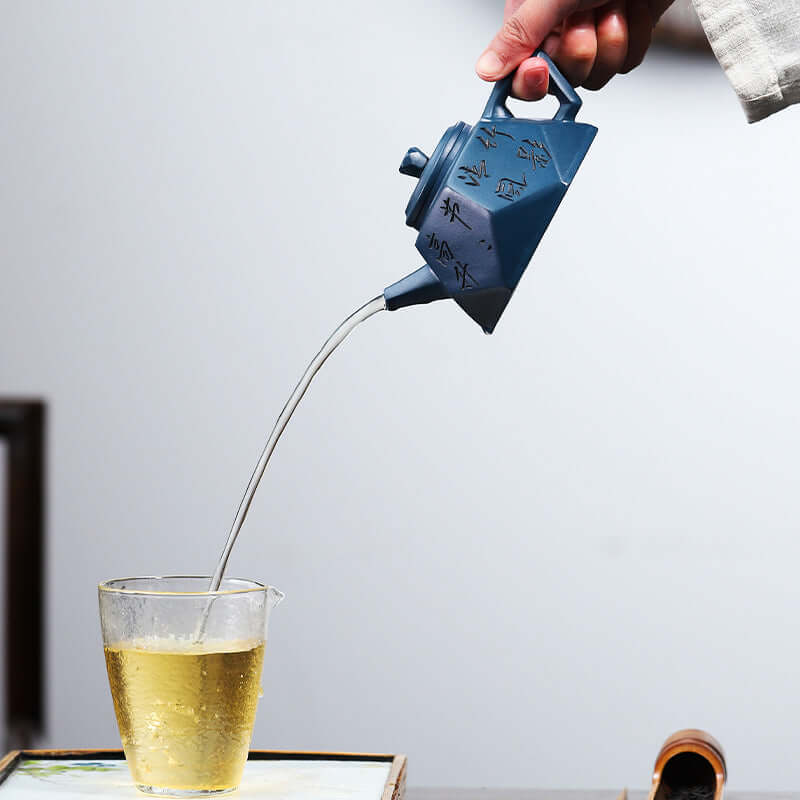 Handmade Yixing purple sand teapot pouring tea into a glass cup, showcasing craftsmanship and elegant design.