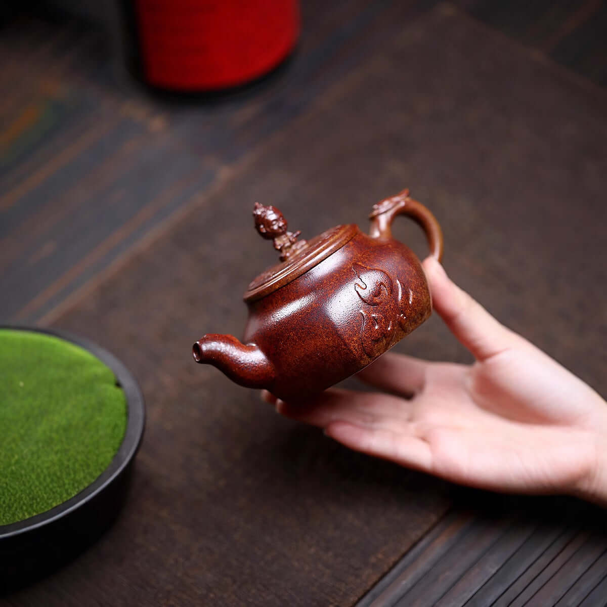 Handmade Yixing purple sand teapot held in hand, showcasing traditional craftsmanship and ancient firewood burning method.