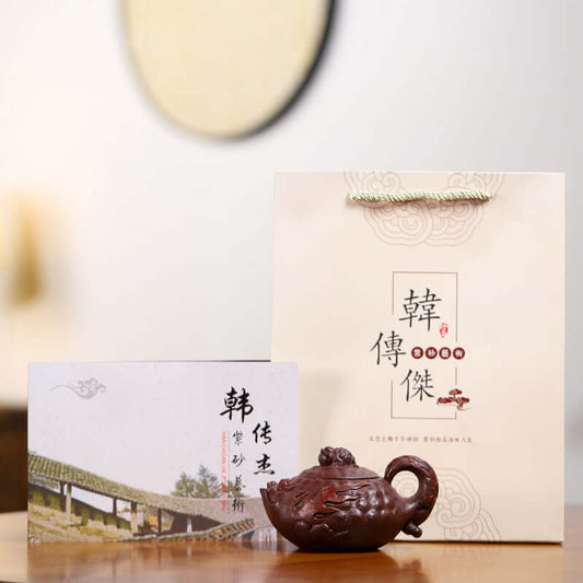 Handmade Yixing purple sand teapot displayed with certificate and gift bag, showcasing traditional craftsmanship.
