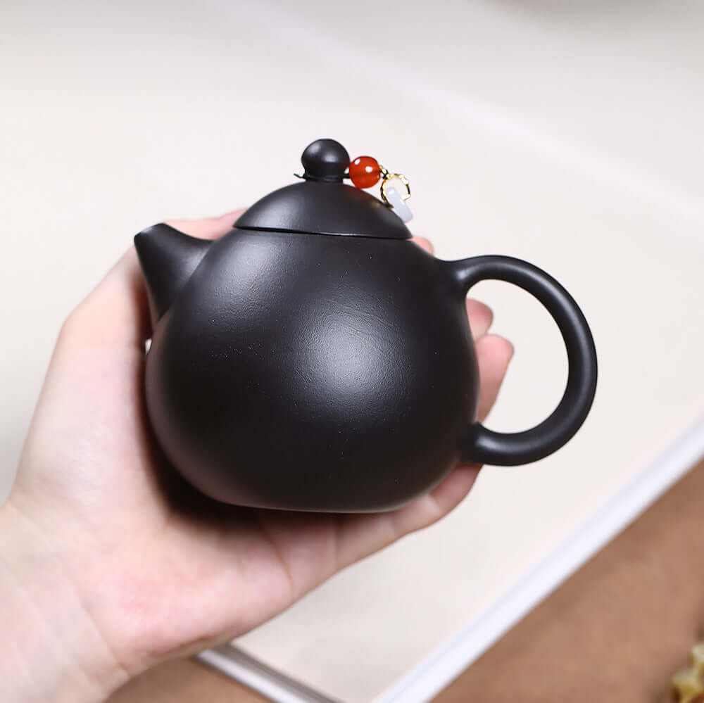 Handmade Yixing purple sand teapot in black, showcasing unique craftsmanship and design for tea enthusiasts.