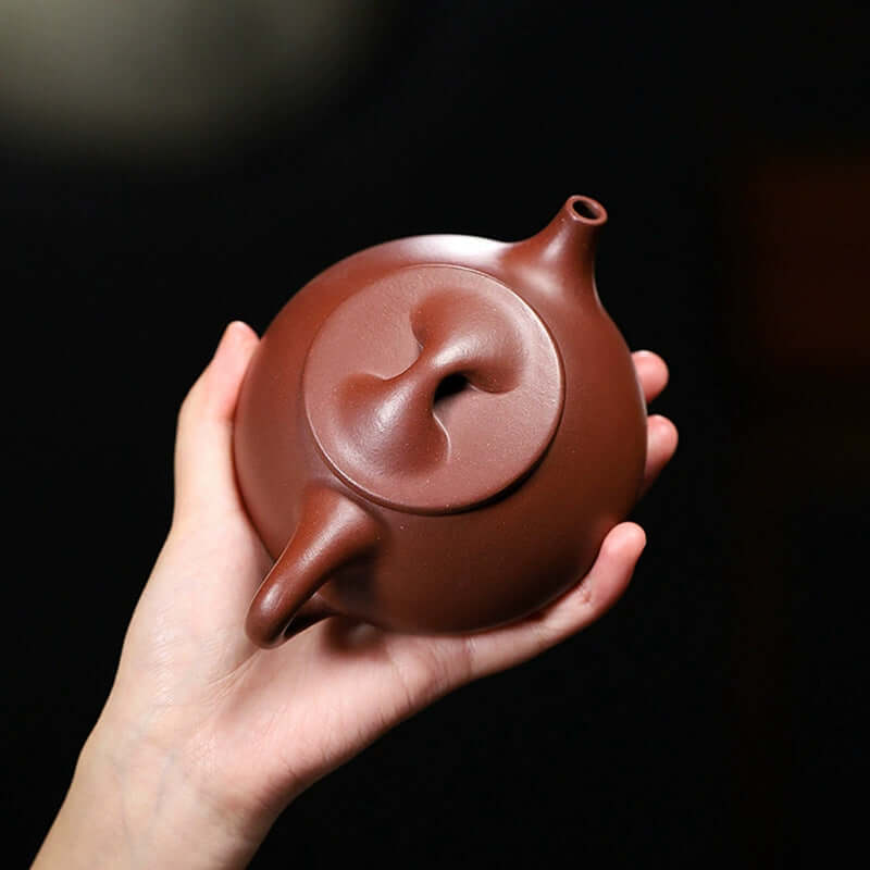 Handmade Yixing purple sand teapot, crafted with original purple sand, showcasing a unique design in a hand.