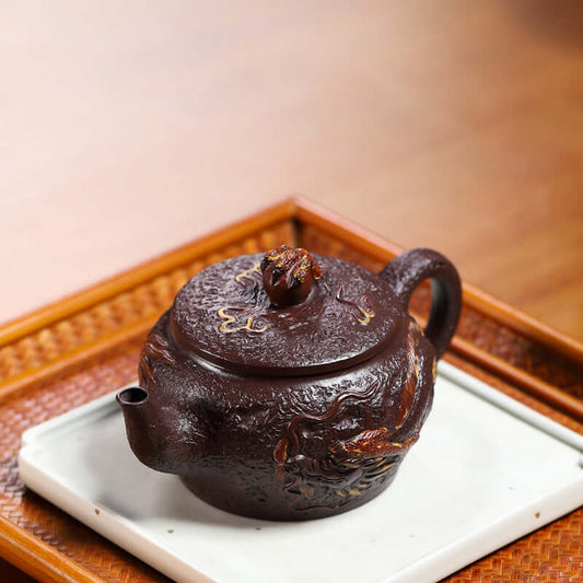 Handmade Yixing purple sand teapot featuring a dragon design, displayed on a traditional tea tray.