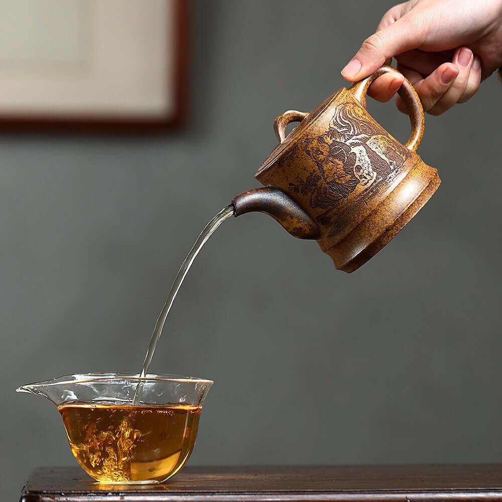Handmade Yixing purple sand teapot pouring tea into a glass cup, showcasing traditional craftsmanship and elegance.