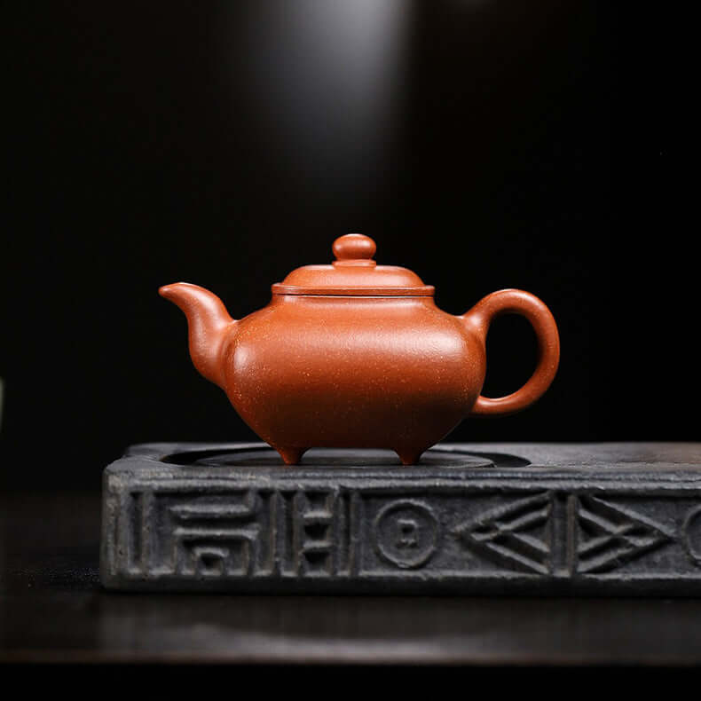 Handmade Yixing purple sand teapot on decorative base, showcasing unique craftsmanship and vibrant color.