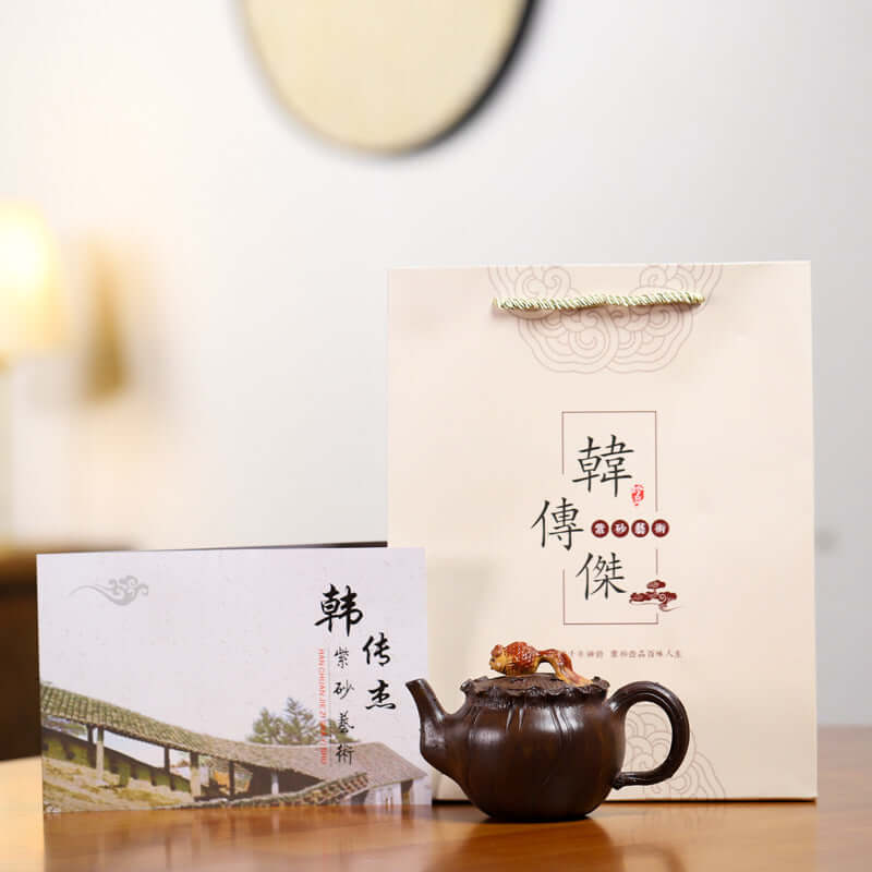 Handmade Yixing purple sand teapot with packaging and certificate displayed on a table.