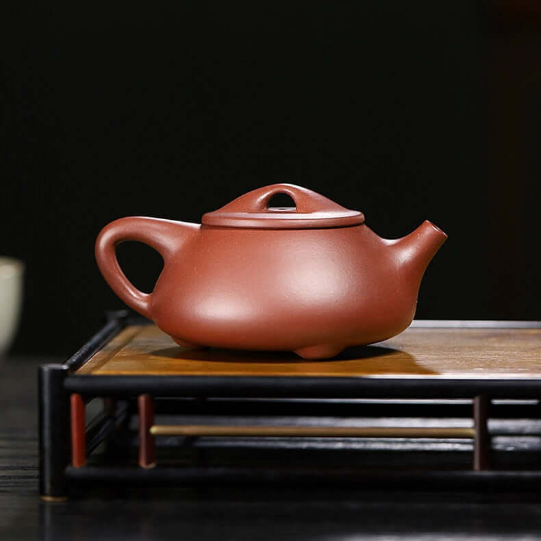 Handmade Yixing purple sand teapot on a bamboo tray, showcasing original craftsmanship and artisanal quality.