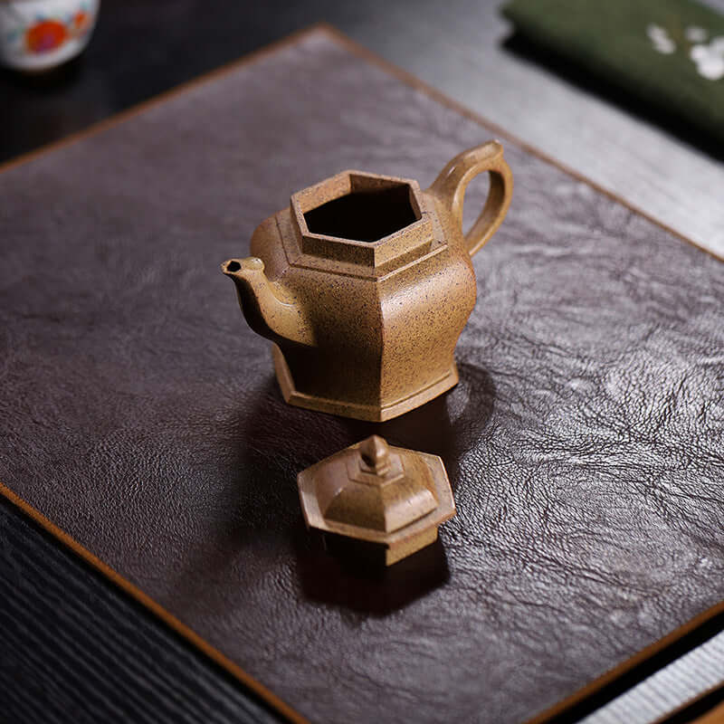 Handmade Yixing purple sand teapot with lid on a textured surface, showcasing original craftsmanship and unique design.