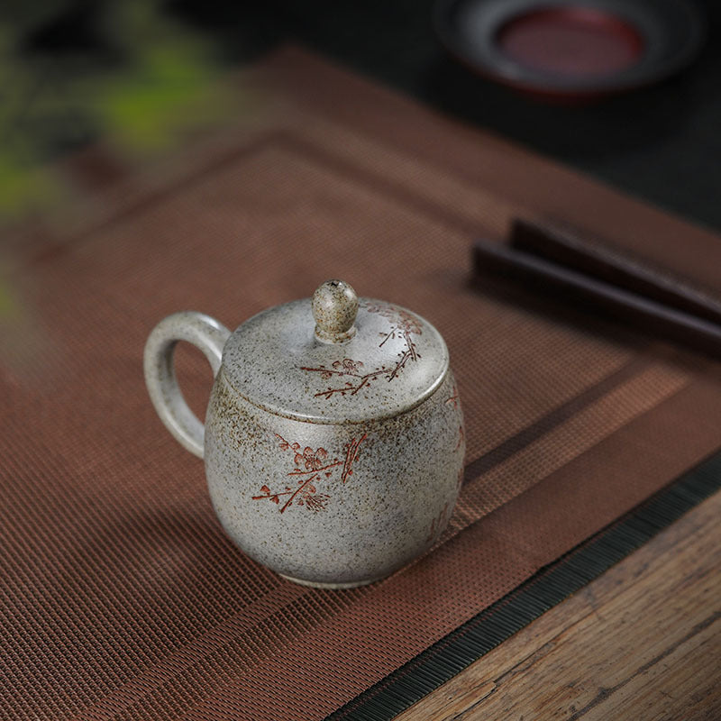 Handmade Yixing purple sand cup with plum blossom design, featuring a lid, perfect for tea. Original purple sand craftsmanship.