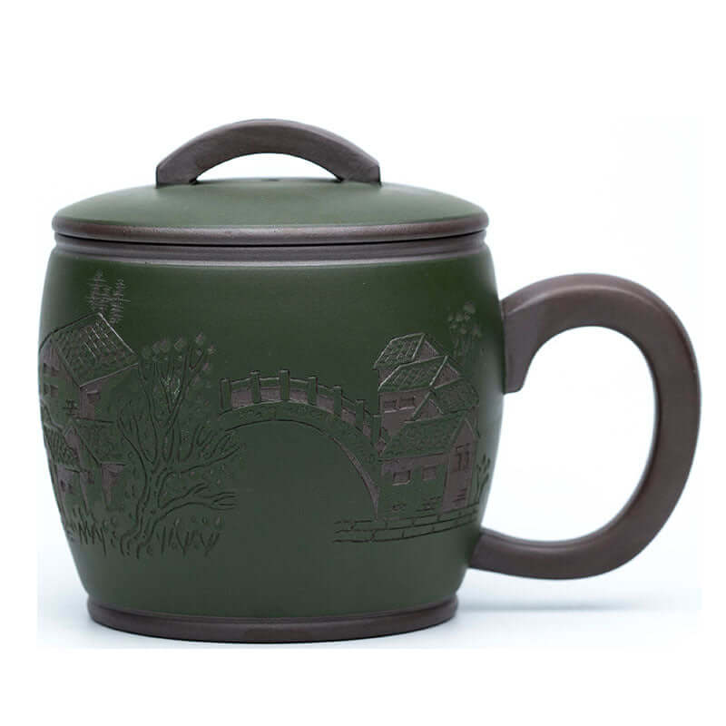 Handmade Yixing purple sand cup with green mud finish, featuring intricate village scene, perfect for tea enthusiasts.