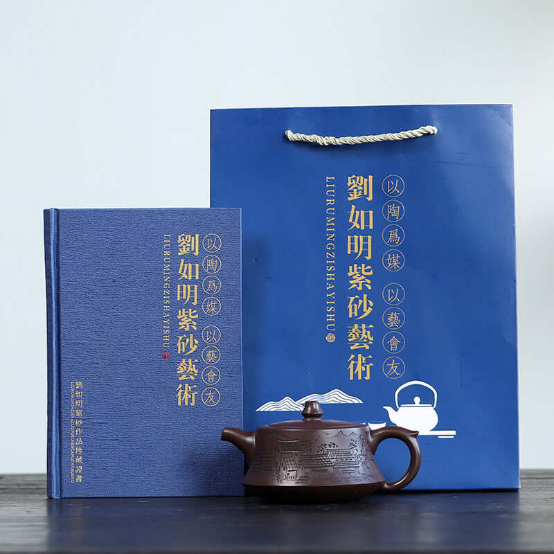Handmade Yixing purple sand teapot, art book, and gift bag by Liu Ruming, showcased on a minimalist background.