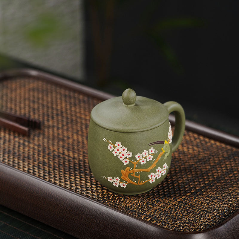 Handmade Yixing purple sand teapot with floral design on green finish, crafted by skilled artisans.