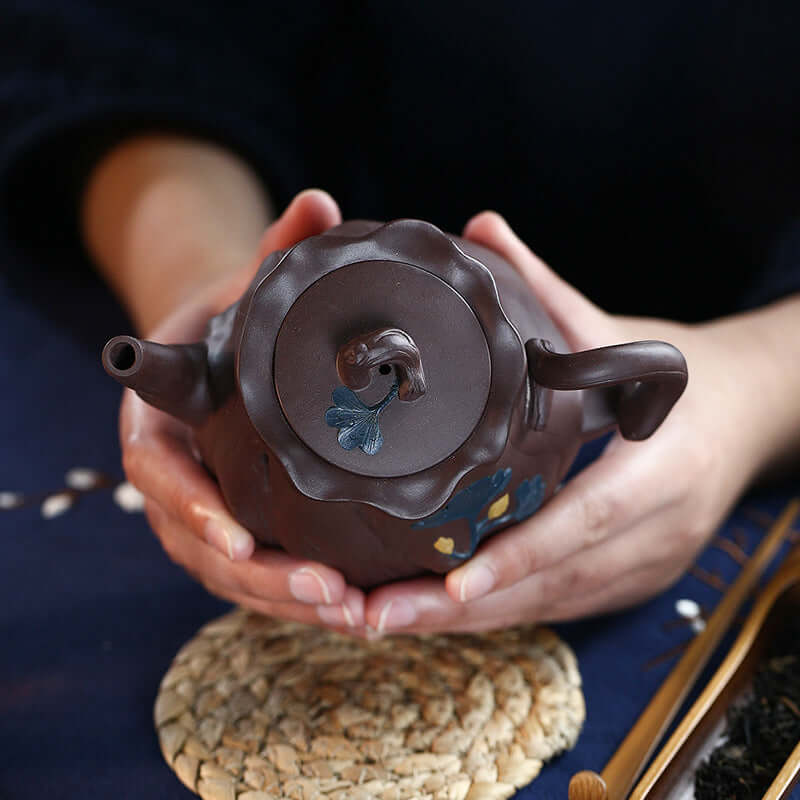 Handmade Yixing purple sand teapot held in hands, showcasing intricate details and original design.