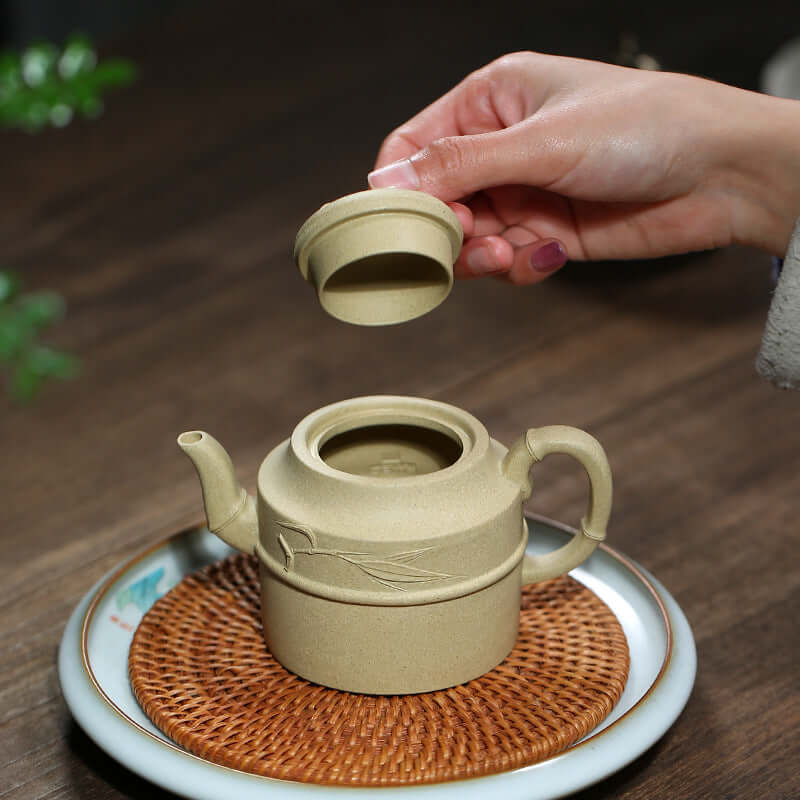 Handmade Yixing purple sand teapot being served, showcasing unique bamboo design and natural texture on a wooden table.