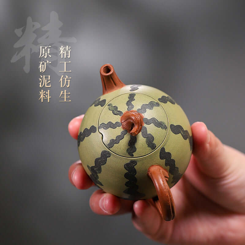 Handmade Yixing purple sand teapot resembling a watermelon, featuring green clay and intricate black designs.