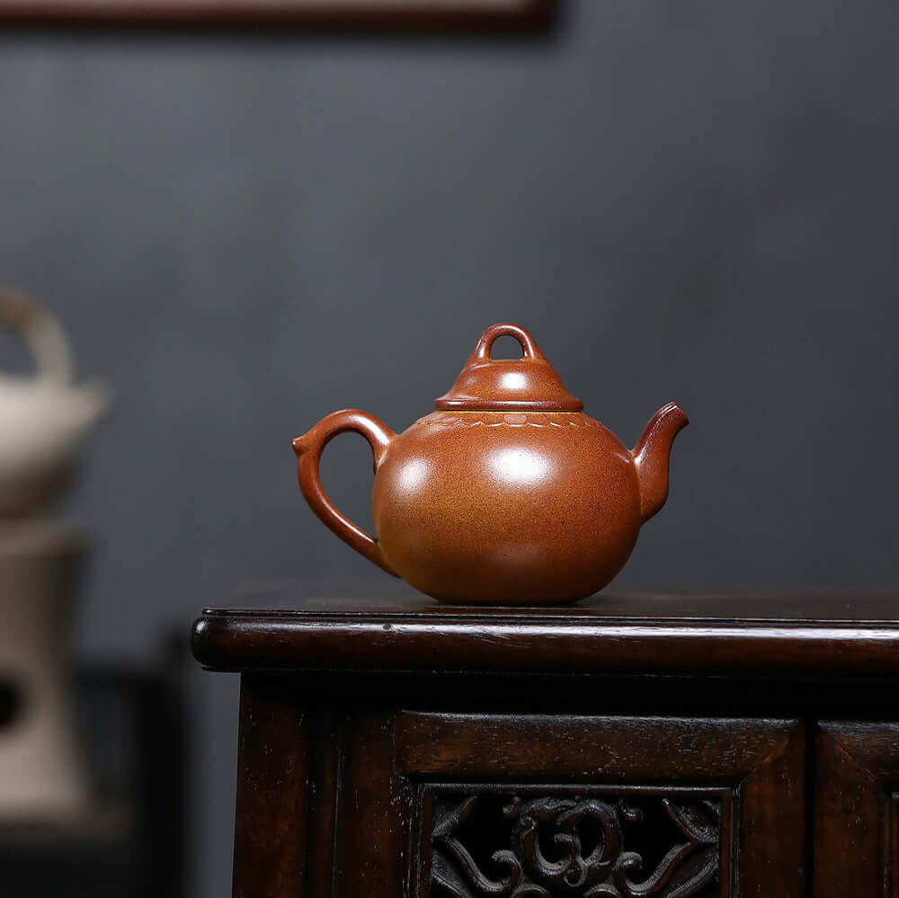 Handmade Yixing purple sand teapot on a wooden table, showcasing traditional craftsmanship and unique design.