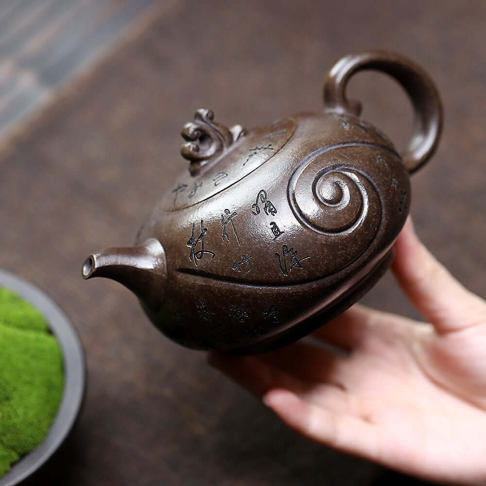 Handmade Yixing purple sand teapot in hand, featuring ancient copper mud and intricate calligraphy design.