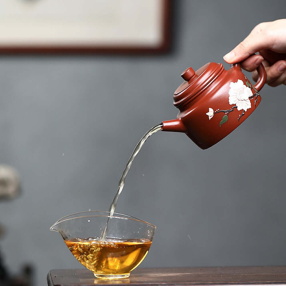 Handmade Yixing purple sand teapot pouring tea into a glass cup, showcasing traditional Kung Fu tea set craftsmanship.