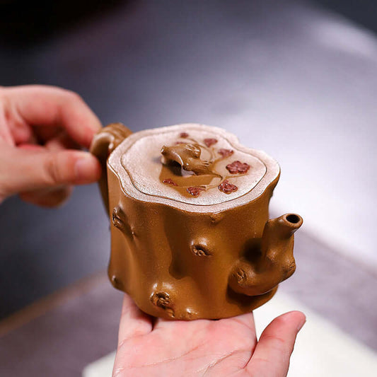 Handmade Yixing purple sand teapot shaped like a plum stump, showcasing intricate craftsmanship and earthy colors.