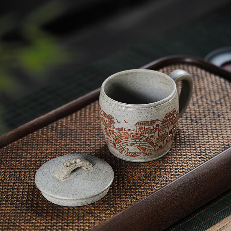 Handmade Yixing purple sand teacup featuring traditional Jiangnan scenery and a fitted lid.