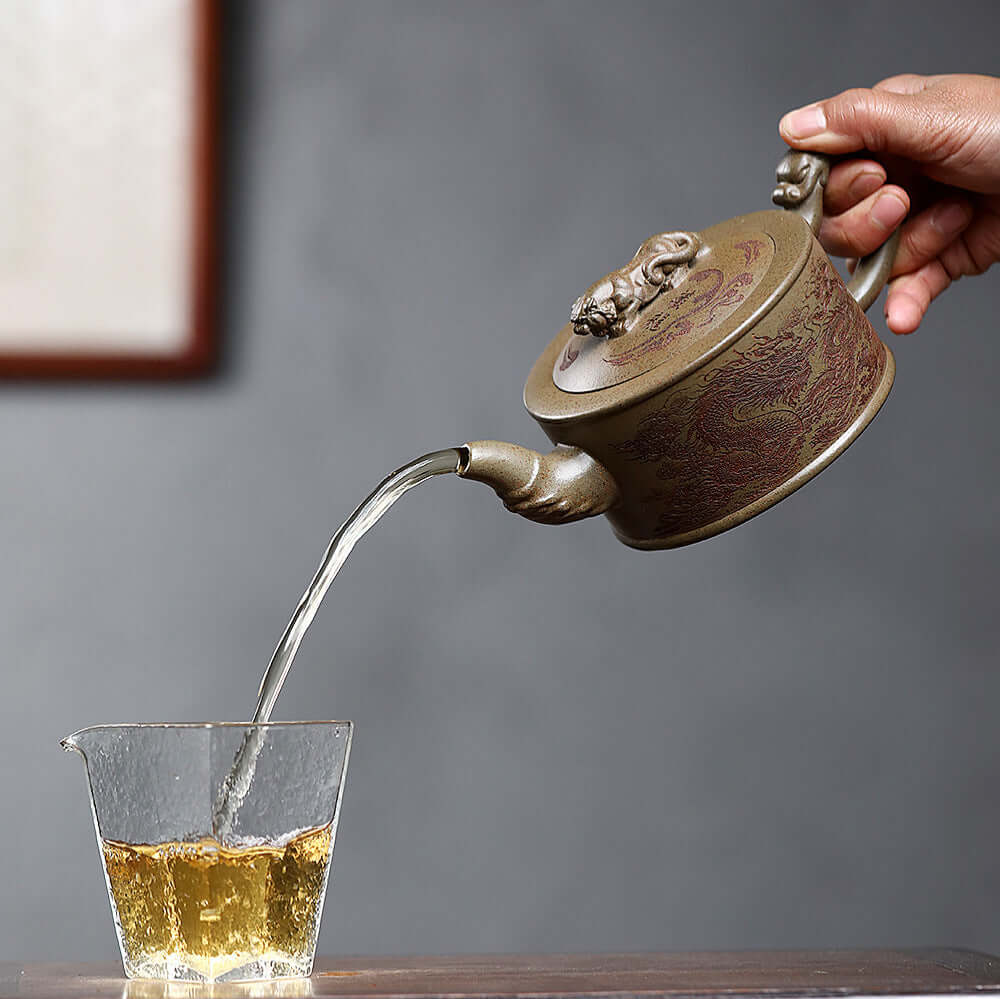 Handmade Yixing purple sand teapot pouring tea into glass, showcasing intricate design and craftsmanship.