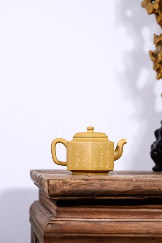 Handmade Yixing purple sand teapot with intricate inscriptions, displayed on a wooden table.
