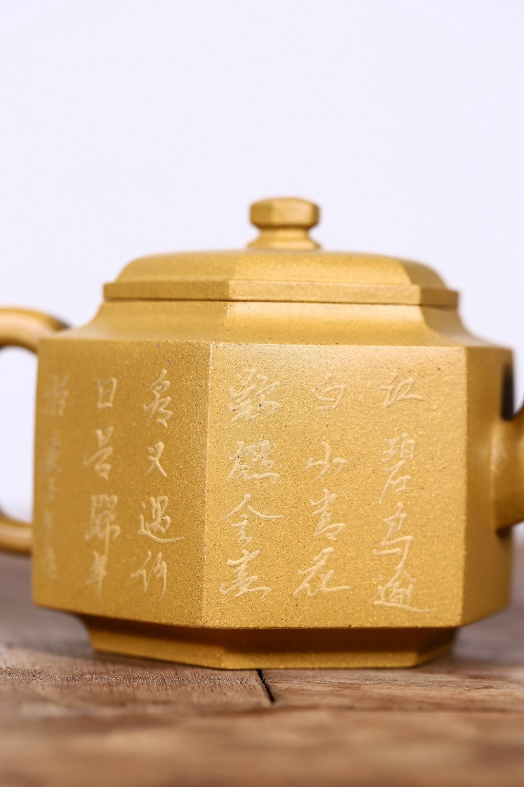 Handmade Yixing purple sand teapot with intricate golden inscriptions, showcasing unique octagonal design.