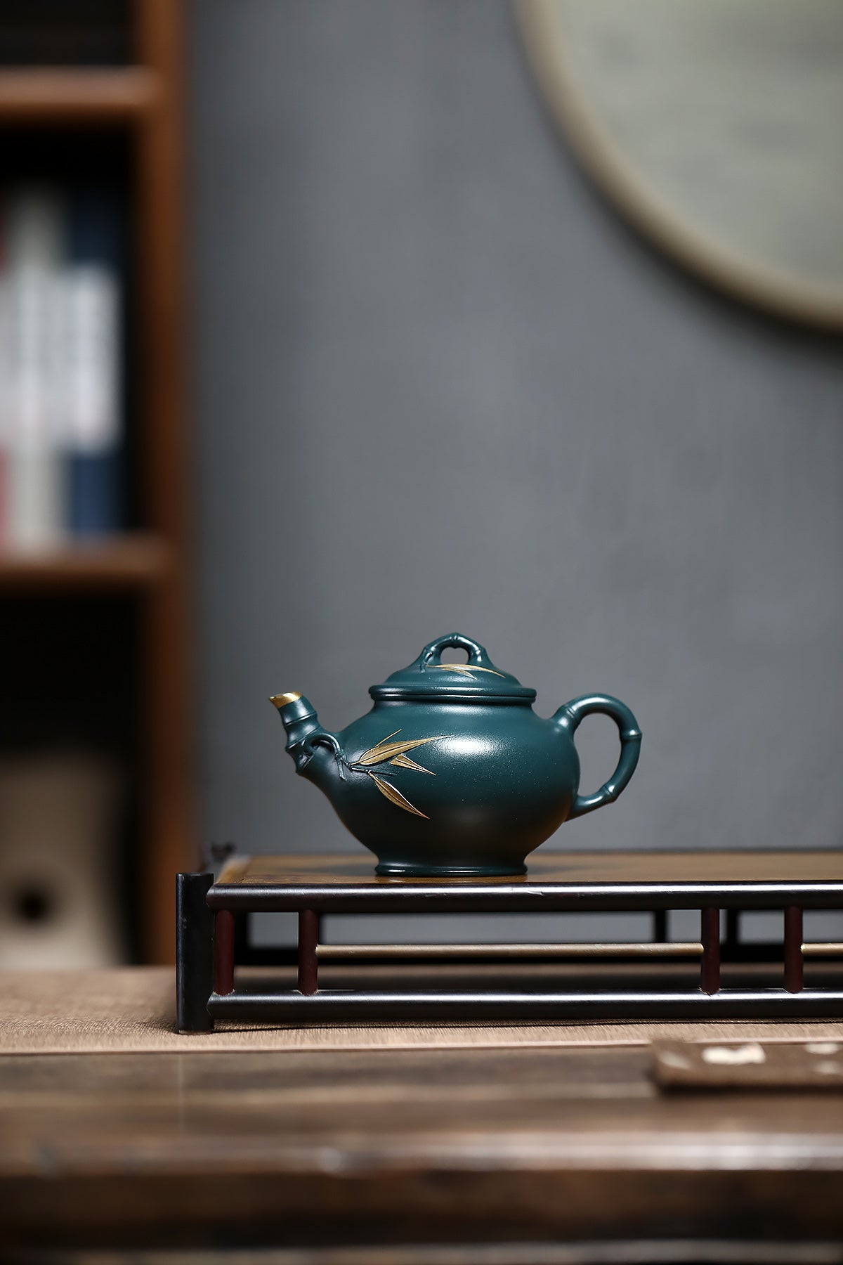 Handmade Yixing purple sand teapot in dark green color, showcasing a bamboo-inspired design, elegantly displayed on a wooden stand.